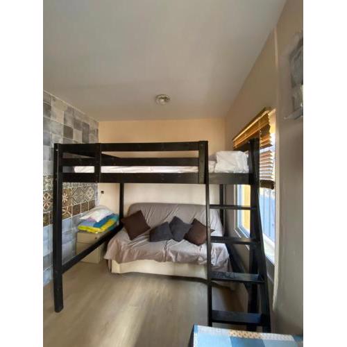 Habitación con cama alta, con baño propio, en casa de vecinos dormitorio número 1, minibar, aire portátil,centro estación